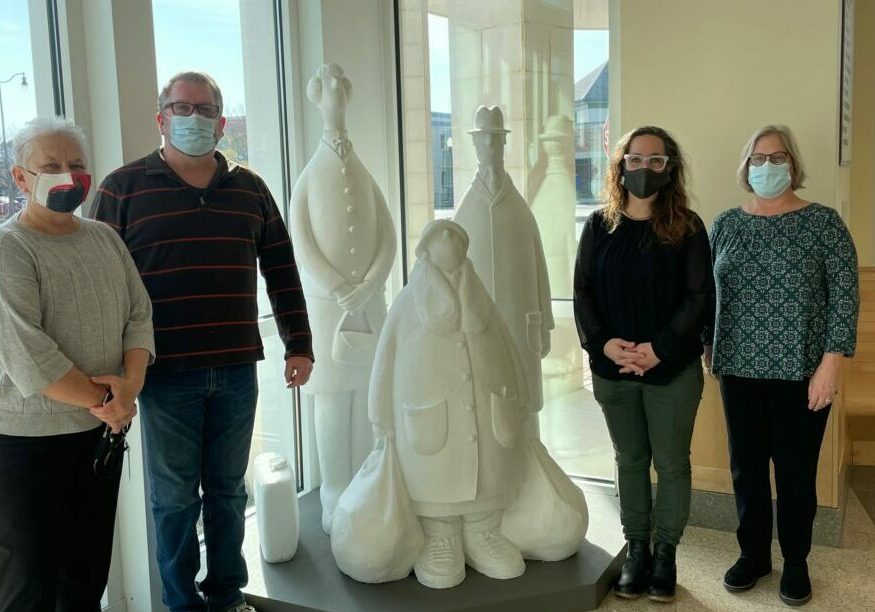 From left, Rehoboth Beach City Manager Sharon Lynn, RAL Exhibitions Coordinator Nick Serratore, RAL Executive Director Sara Ganter, and RAL Choptank Collections Manager Melissa May stand around the sculpture “Bus Stop.” They attended the installation of the sculpture in the atrium at City Hall.