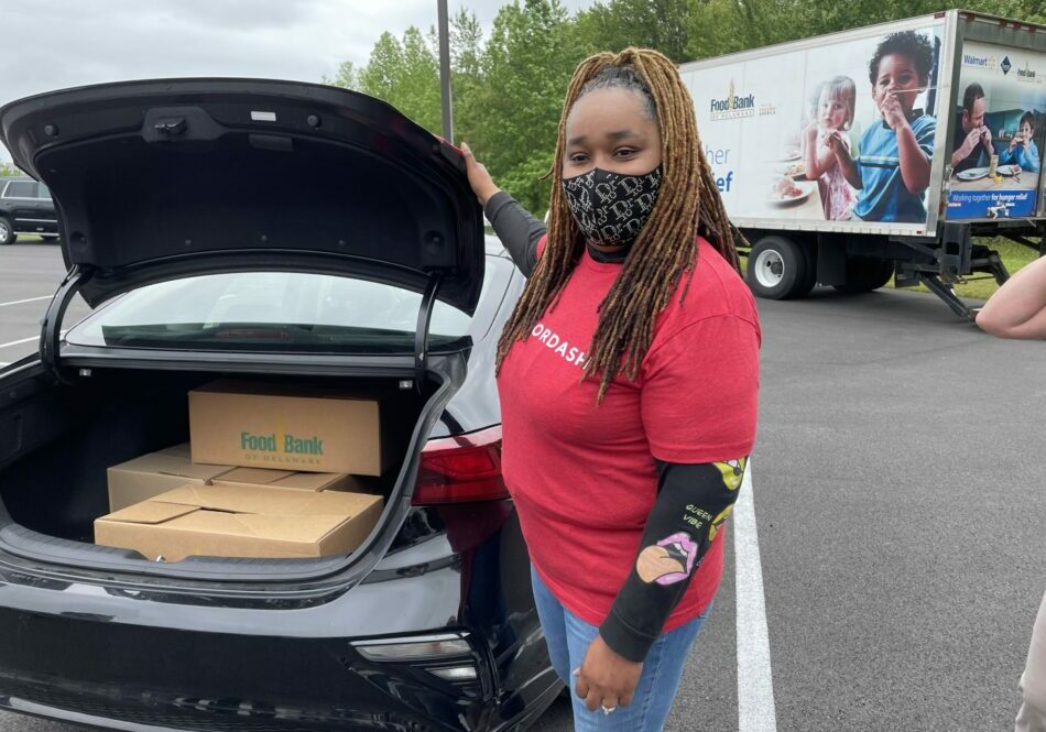 DoorDasher Lydia Conway poses next to her vehicle that’s been loaded with the first DoorDash delivery from the Food Bank of Delaware