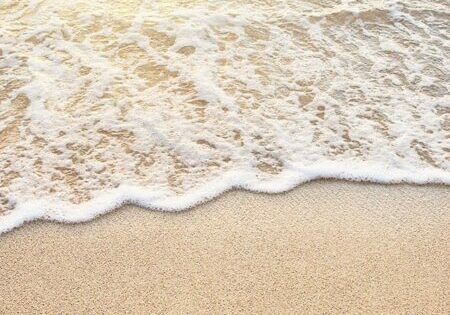 Picutre of wave rolling up beach with sea foam